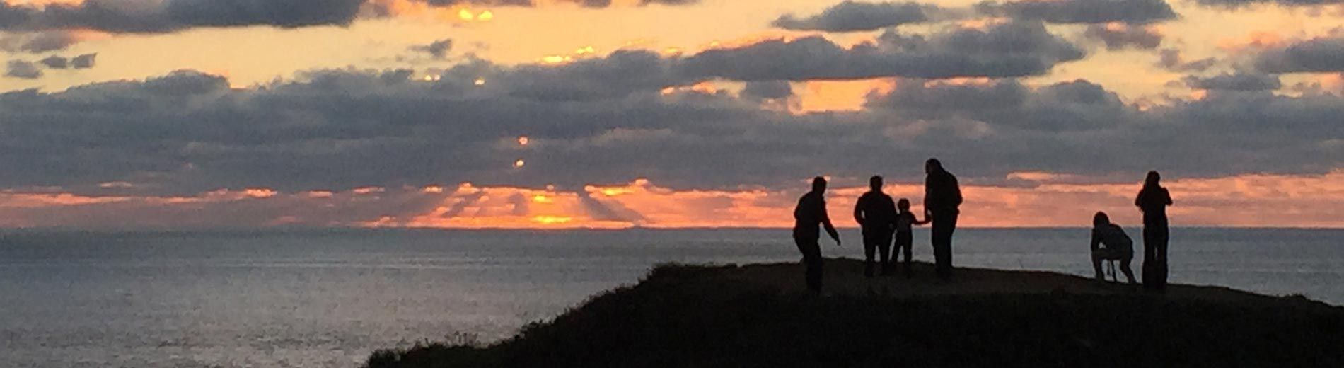 visitors enjoying coast sunset on bluff in front of Moss Beach Distillery
